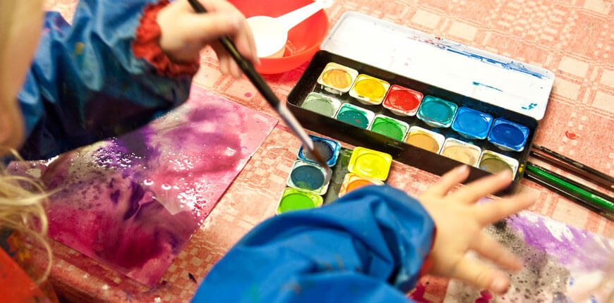 Barnhänder som målar med vattenfärger